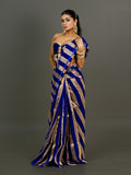 A woman modeling a royal blue and gold striped silk saree with a strapless sweetheart bodice, set against a solid dark gray studio background.